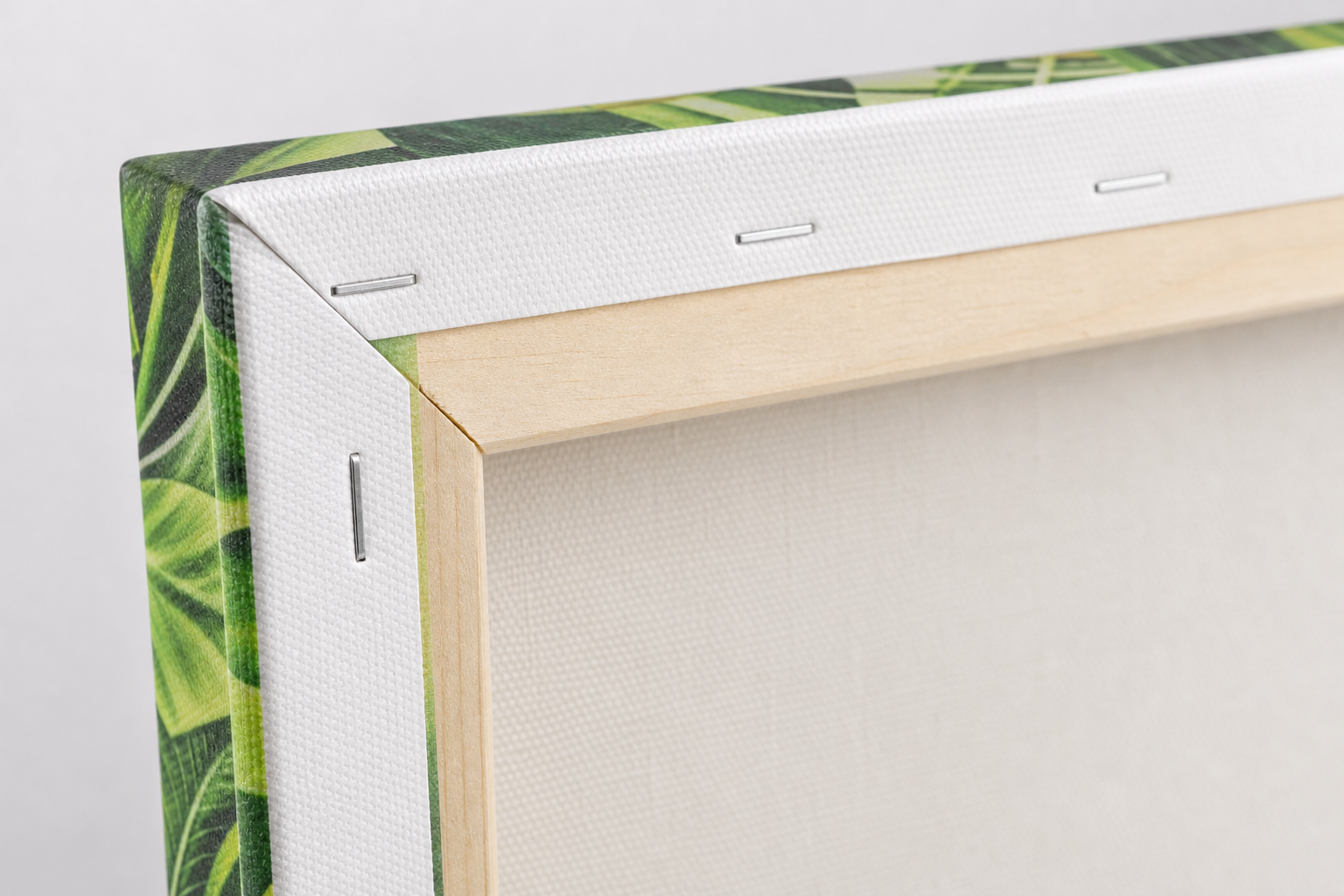 Back of a pine stretcher frame with canvas border stapled down and print wrapping onto the reverse