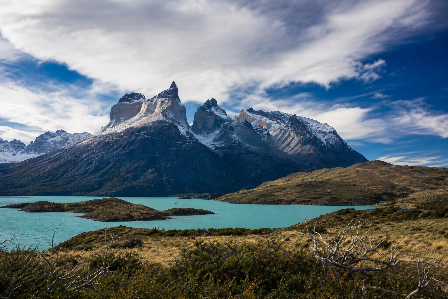 Patagonia mountains Torres del Paine, sharp granite peaks rising above a turquoise glacial lake, windswept grasslands, real photograph, landscape photography
