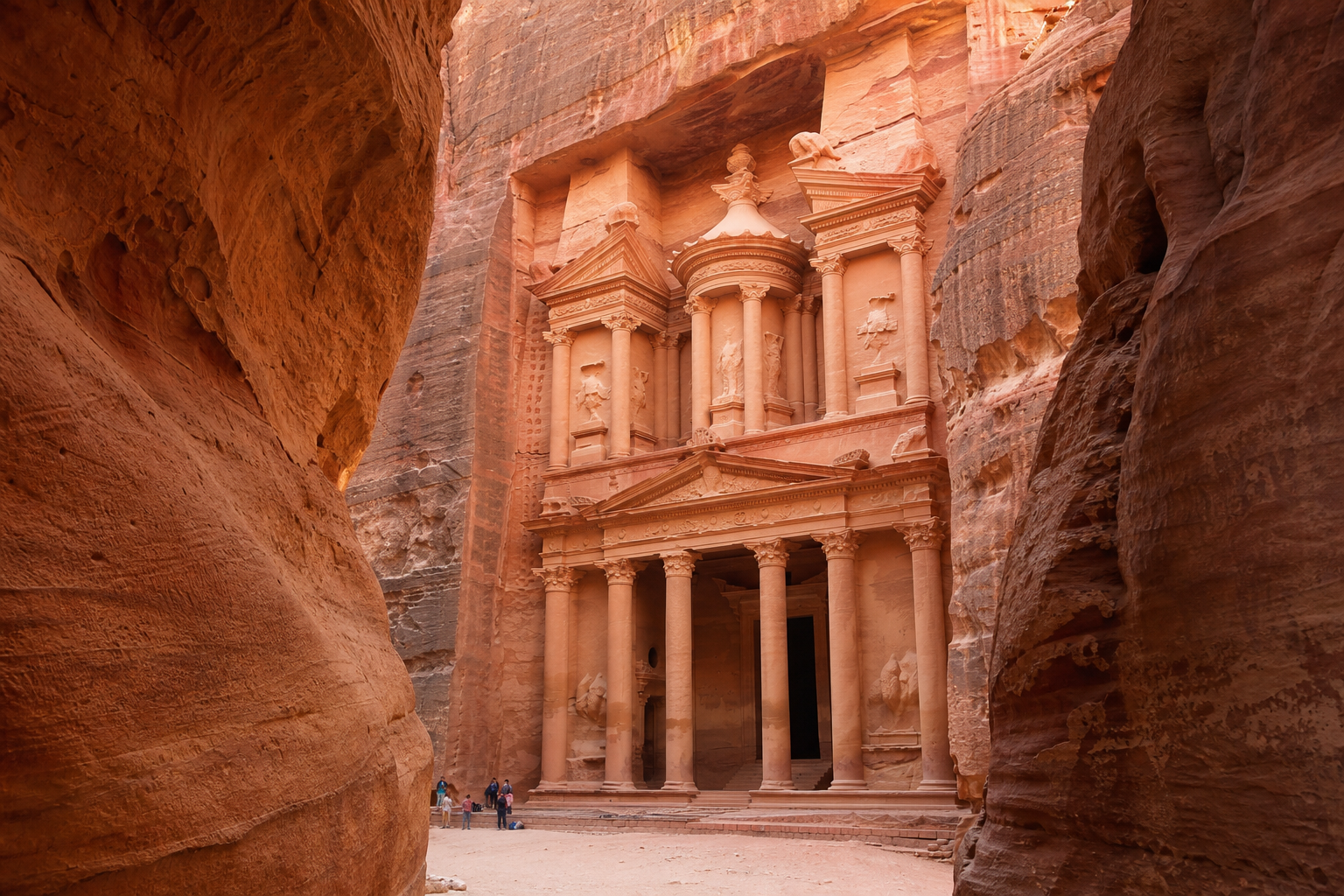 Petra Jordan Treasury facade carved into rose-red sandstone cliff, warm golden desert light illuminating ornate classical columns, real photograph, travel photography